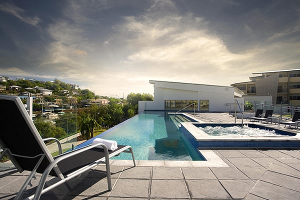 infinity pool and spa with sun lounger and clean towels at sunset at Oaks Gateway Suites hotel in South Townsville